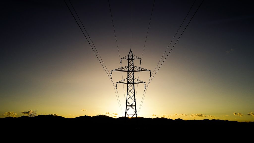 An energy pylon silhouette with a setting sun backdrop