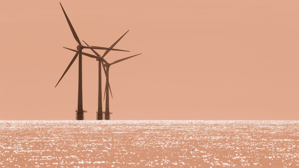 Offshore wind farm at sea under a sunset sky